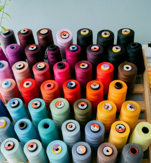 A vibrant collection of sewing threads displayed alongside fabric swatches in a creative studio.